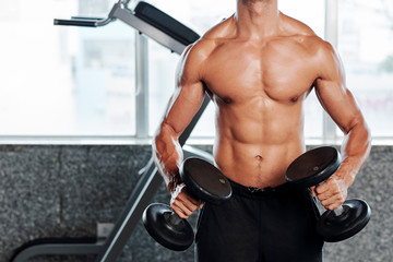  Cropped image of strong sweaty fit man doing exercises with dumbbells