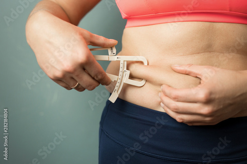 Cuadros en Lienzo Woman measuring her body skin fat with fat caliper