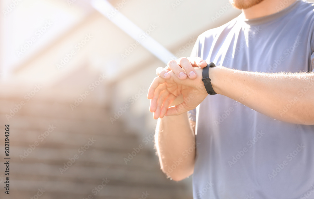 Sporty young man checking his pulse outdoors