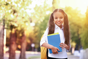 Wall Mural - Cute little schoolgirl after classes outdoors