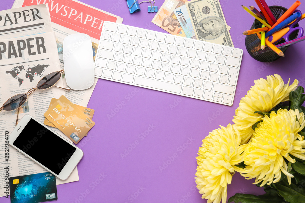 Computer keyboard with mobile phone, newspapers and money on color background