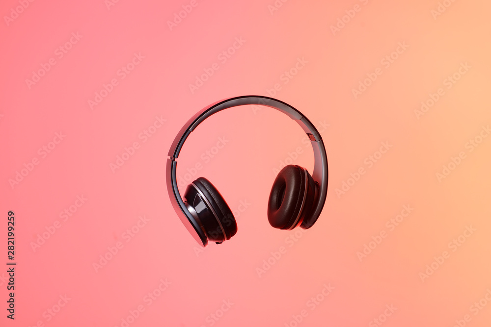 Modern headphones on color background