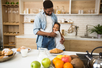 Wall Mural - Thankful afro girl hugging her dad before breakfast