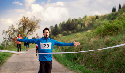 Canvas Print - Man runner crossing finish line in a race competition in nature.