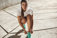 Motivation, Urban Fitness And Running Concept. Determined Alluring Young Fit Female Workout Outdoors, Kneel To Tie Shoelaces On Sneakers, Look Camera Self-assured, Prepare Morning Jogging