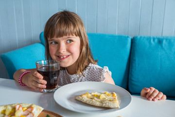 Wall Mural - A happy little girl in a restaurant. A child with a cola in his hands.