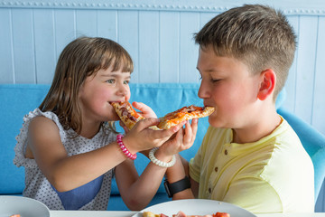 Wall Mural - Kids eating pizza indoors. Fast food. Close-up.