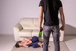 Alcoholism, abuse and domestic violence - Woman lying on the floor, afraid of men with bottle