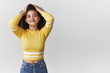 canvas print picture - Attractive carefree relaxed modern young mixed-race curly-haired girlfriend wearing stylish cropped top touch hair hold hands head loose standing joyful smiling pleased enjoy perfect party