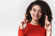 © Cookie Studio - Close-up tender feminine young happy supportive dark-haired woman curly hairstyle cross fingers good luck smiling anticipating good news miracle wish come true, standing white background