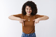 © Cookie Studio - Hmm intersting what inside. Intrigued alluring young cheerful curly-haired girl looking pointing down curiously wondering smiling excited standing white background entertained