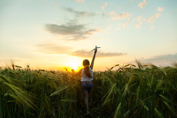 Wall Mural - Child girl holding airplane toy during running in the field