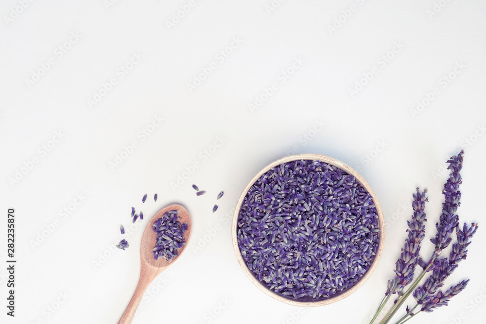 Lavender flowers in wooden plate and spoon, branches on white background, toned. Spa, recipe concept. Top view, close-up, flat lay, copy space, layout design - obrazy, fototapety, plakaty 