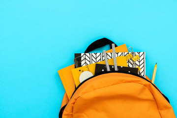 Wall Mural - Back to school concept. Backpack with school supplies on blue background. Top view. Copy space. Flat lay