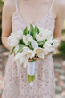 © oksana_bondar - Bride Hold in Hand Tulip Wedding Bouquet Outside. Detailed Shot of Woman with Bunch of White Flowers Decorated with Satin Ribbon. Outdoor Marriage Ceremony Detail Shallow Focus. Summer Event