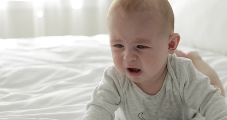 Wall Mural - Upset little child crying on bed at home