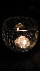 Lighted candle in an artificially aged glass candlestick