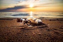 Message In The Bottle Against The Sun Setting Down