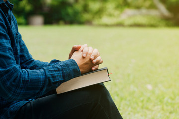 Wall Mural - Christians and Bible study concept.Young man sitting and prayer on bible.copy space