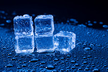 Wet Ice Cubes And Water Drop On Blue Background.