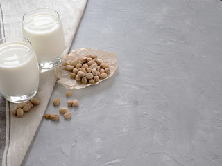 Pistachio milk in a glass Cup and pistachio nuts on a gray concrete background. Copy space.