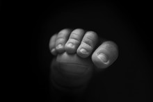 Little Foot Of A Newborn Baby On A Black Background Close-up