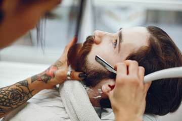 Man with a beard. Hairdresser with a client. Woman with a shaving gel