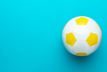 Top View Photo Of White And Yellow Soccer Ball As Football Concept . Minimalist Flat Lay Image Of Leather Football Ball Over Blue Turquoise Background With Copy Space And Right Side Composition.