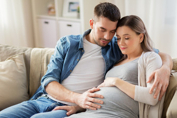 Canvas Print - pregnancy and people concept - happy man hugging pregnant woman at home