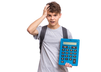 Poster - Surprised student holding big calculator. Portrait of funny cute teen boy touching his head with hand, isolated on white background. Shocked child with calculator looking at camera. Back to school.