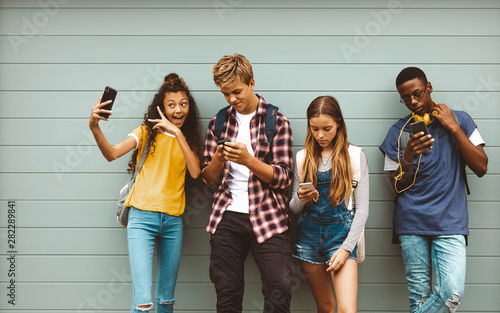 Fotomural Teenage friends looking at their mobile phones