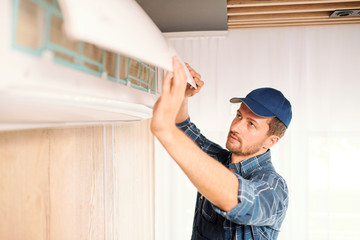 Young electrician or repiar service technician opening lid of air conditioner