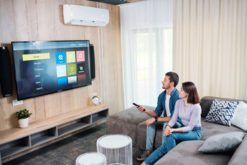 Young man and his wife choosing something to watch on digital display