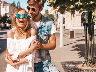 Smiling beautiful girl and her handsome boyfriend. Woman in casual summer dress and man in jeans clothes. Happy cheerful family. Female having fun on the street background.Hugging couple in sunglasses