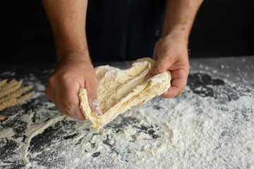 chef cooks pizza, strong male chef hands tear raw dough into pieces,