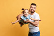© the faces - excited dad and his daughter looking at the camera while having fun. close up photo. isolatedyellow background. studio shot, happiness concept