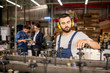 © pressmaster - Young bearded mechanic in protective headphones repairing industrial machine