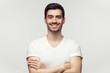 © Damir Khabirov - Portrait of smiling attractive man in white t-shirt standing with crossed arms isolated on gray background