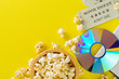 © Shawn Hempel - Movie tickets, DVD or blu ray disc and popcorn on yellow table background. Home theatre movie or series night concept. Flat lay top view from above with copy space