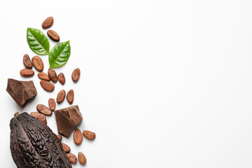 Cocoa pod with beans and chocolate pieces on white background, top view