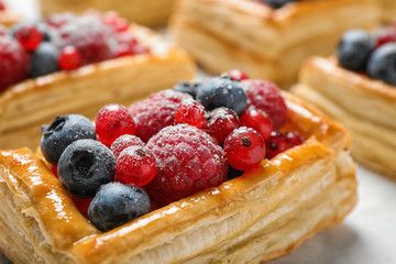 Fresh delicious puff pastry with sweet berries on light table, closeup