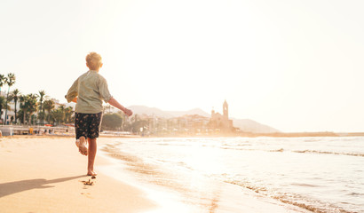 Wall Mural - Happy little boy running by Mediterranean spain coast in Sitges town near Barcelona