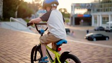 Child Riding Bicycle In Park At Sunset Light. Kid In Helmet Learning To Ride At Summer. Happy Boy Riding Bike, Having Fun Outdoors On Nature. Active Sport Family Leisure. Healthy Holidays. Slow Motion