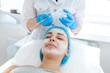 © Kate - A professional cosmetologist applies a nourishing cream on the patient's face. Moisturizing, cleaning and facial skin care. Cosmetic procedures