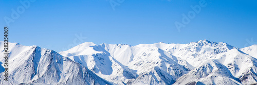 Fototapeta Mountain peaks snow covered mountain range with blue sky