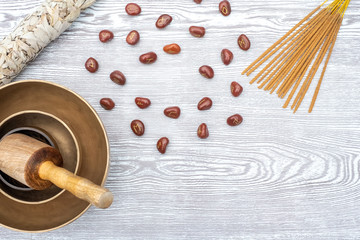 Flat lay composition of rune stones, dried white sage, incense and Tibetan singing bowls on a wooden background