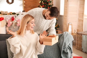 Canvas Print - Happy man giving his wife Christmas present at home