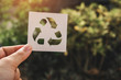 © panadda - Hand holding recycling symbol created with paper cut and landscape on background, Concept of environmental conservation and protection.