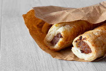 Sausage rolls in a brown paper bag, environmentally friendly biodegradable packaging, with a grey wood background