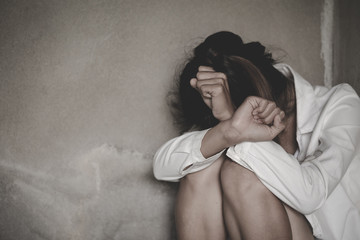 Depression or domestic violence Concept, Black and white image of a young woman crying and covering her face useful to illustrate stress.